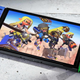 A Splatoon 3-themed Switch OLED model sits on concrete as its characters line-up onscreen.